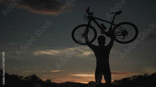 Man is Carrying a bicycle , on the background of rocky trail in mountain area bike on trail at evening.mountain bike racing.healthy lifestyle.xtreme sports.vintage tone.selective focus.lowkeylight.