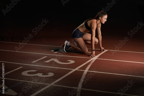 Woman athlete sprinter preparing for start on the sport arena