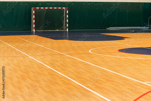Gym for playing futsal, mini-football. Folded wooden parquet on the field of hall for mini-football. Futsal ball and bright line markings on the floor. Floor sports hall with bright lines of marking