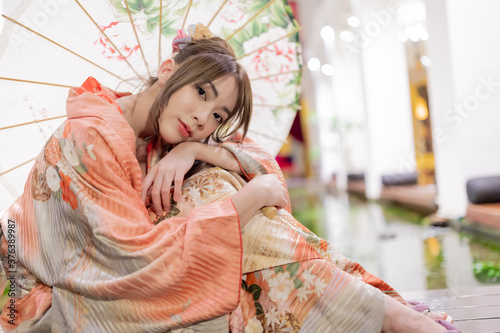 Photo Young woman in traditional Japanese kimono with an umbrella  and looking at camera, Japanese concept of kimono and yukata