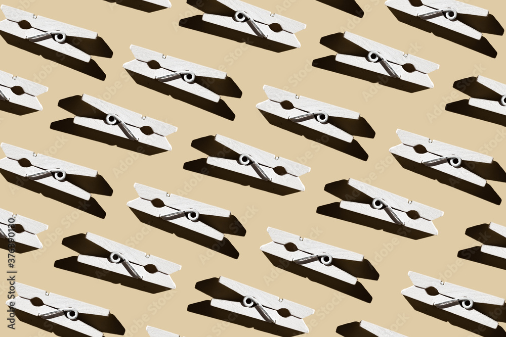 Naklejka premium Pattern of wooden white clothespins on a pastel beige background.