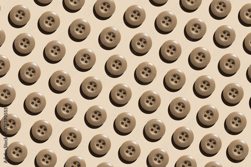 A pattern of beige round plastic buttons on a pastel beige background. The concept of needlework, sewing clothes. A pattern of beige round plastic buttons on a pastel beige background. The concept of needlework, sewing clothes.
