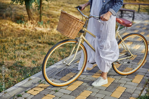 Stylish woman holding handlebar of a city bike with basket
