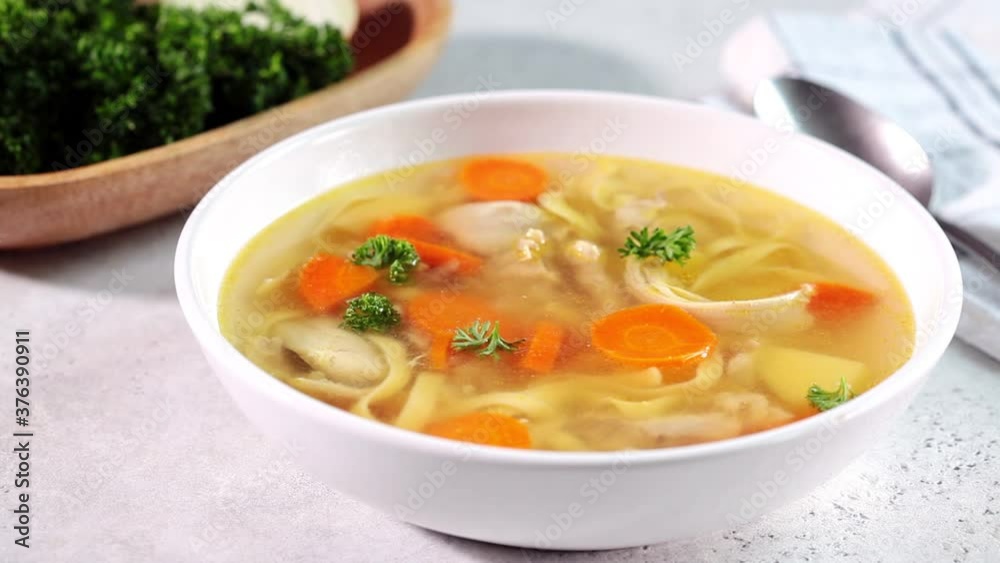 Homemade chicken soup with noodles and vegetables in white bowl, white background. Healthy warm comfortable food. Homemade chicken soup with noodles and vegetables in white bowl, white background. Healthy warm comfortable food.
