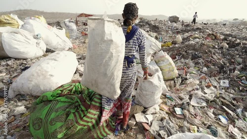 Young people working on landfill site recycling plastics and cardboard. India.