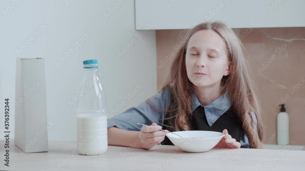 A beautiful girl is having breakfast with cereals. Happy girl eating in the kitchen. Morning routine. School fees. Proper nutrition. A beautiful girl is having breakfast with cereals. Happy girl eating in the kitchen. Morning routine. School fees. Proper nutrition.
