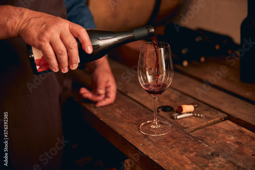 Male sommelier pouring red wine into glass