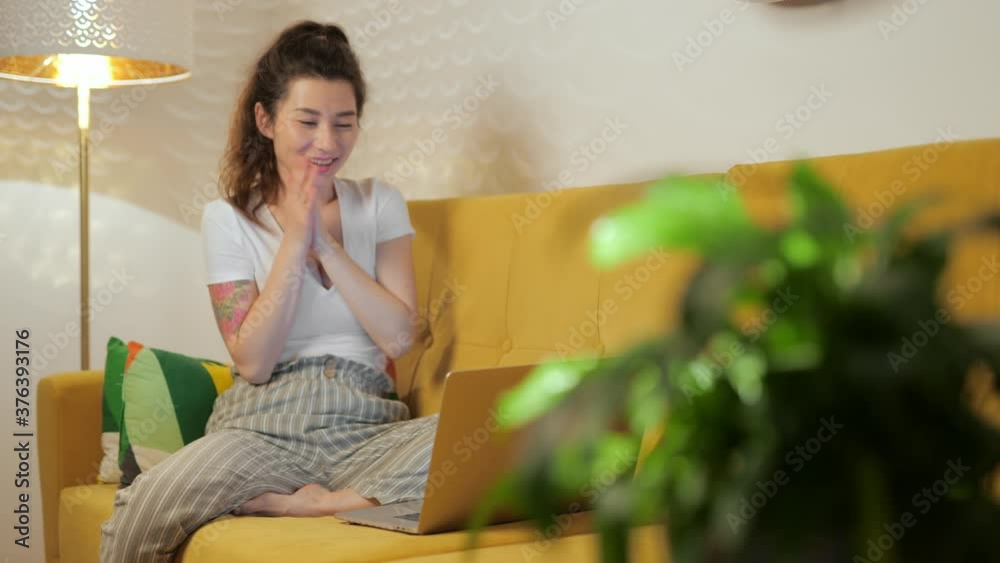 Pretty woman chatting online at home with friends sitting on coach. Pretty woman chatting online at home with friends sitting on coach.