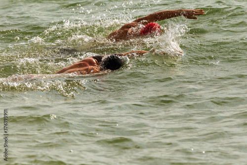 Swimmer swims in sea. Athlete triathlete swimmer drains from water. A professional athlete in triathletes trains for an ironman. The sportsman beautifully floats in blue sea water at competitions © Elena