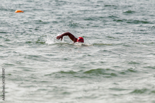 Swimmer swims in sea. Athlete triathlete swimmer drains from water. A professional athlete in triathletes trains for an ironman. The sportsman beautifully floats in blue sea water at competitions