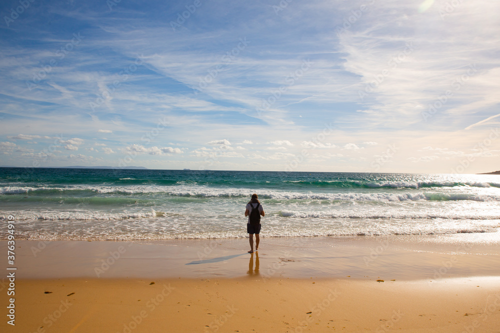 Young man on the shore of the long beach of Zahara de los Atunes in the Atlantic Ocean, Cadiz, Spain