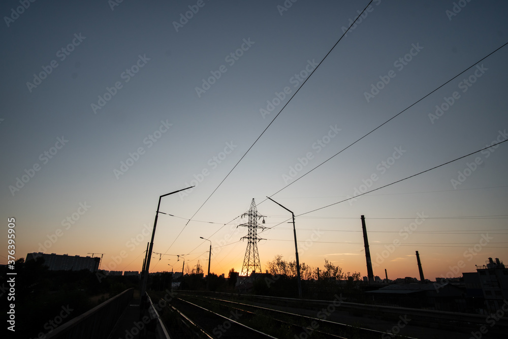 Country landscape, power lines and pylons at sunset at dusk.