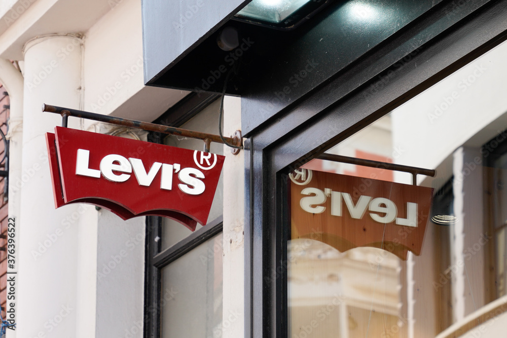 Levi's logo red sign and text front of Jeans levis store of clothing  fashion levi strauss retail shop with windows reflection Stock Photo |  Adobe Stock
