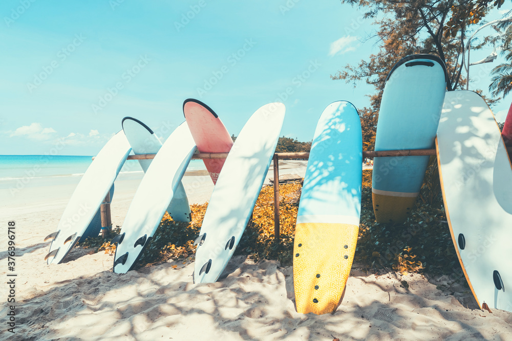 Surfboard on tropical beach with blue sky background. Summer vacation and sport extreme concept.