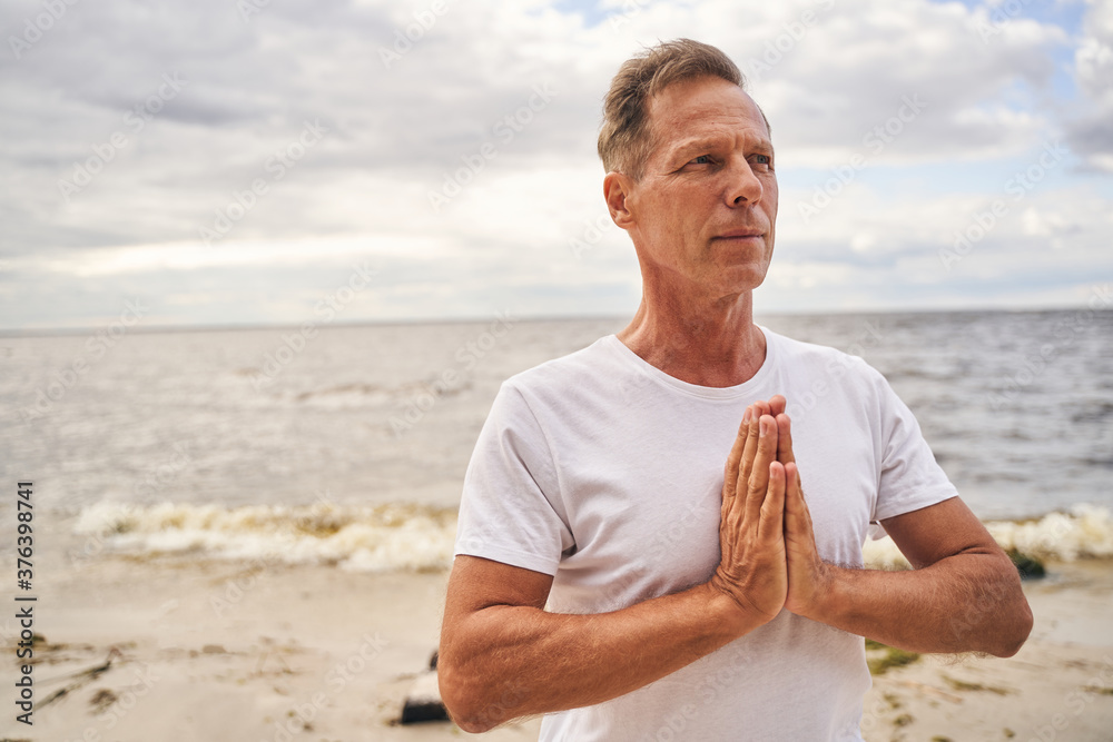 Mature man meditating alone on sea shore
