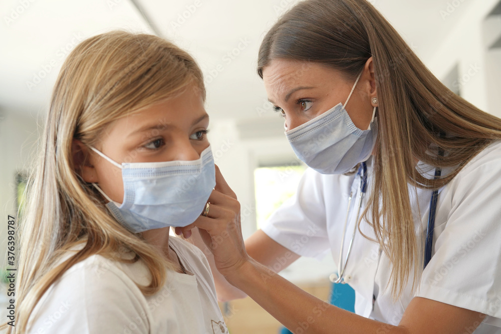 Kid at doctor's office with protection face mask having temperature checked