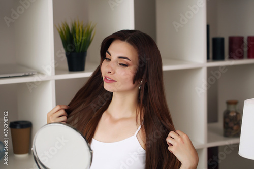 Smiling beautiful girl apply facial skin cream to look in the mirror