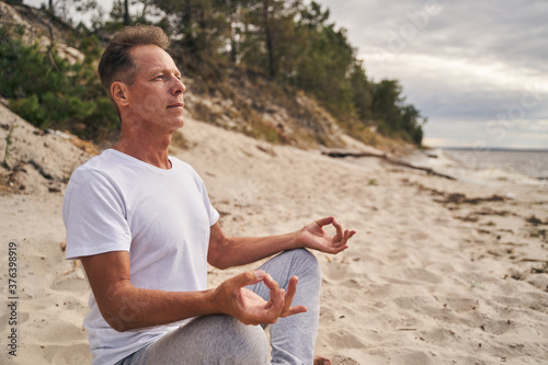 Man relaxing during meditation in inhabitant beach