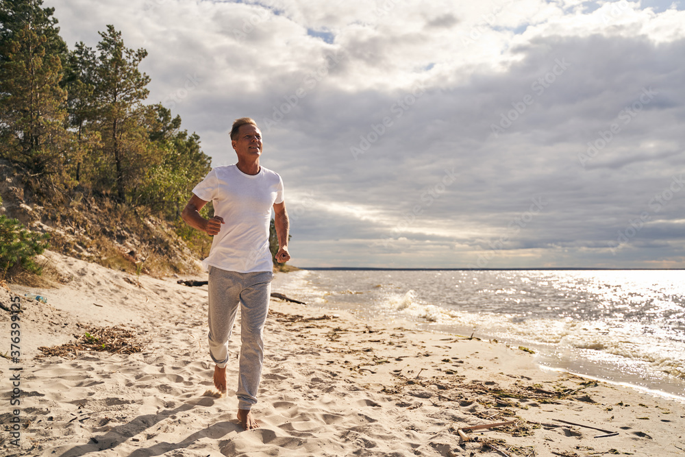 Happy male running alone along sea shore