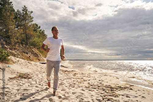 Happy male running alone along sea shore