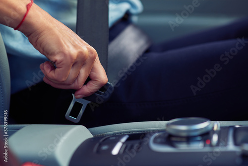 Safety. Cropped shot of a woman sitting behind steering wheel of her car and fastening seat belt © Kostiantyn