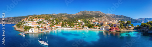Panoramablick auf das idyllische Dorf Asos mit türkisem Meer, Segelbooten und bunten Häusern direkt am Meer, Kefalonia, Griechenland 
