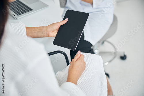 Woman with a gadget having a consultation with a cosmetician