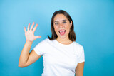 Young beautiful woman over isolated blue background showing and pointing up with fingers number five while smiling confident and happy