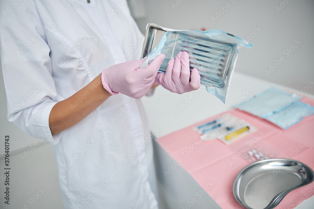 Doctor in latex gloves holding a surgical instrument Doctor in latex gloves holding a surgical instrument