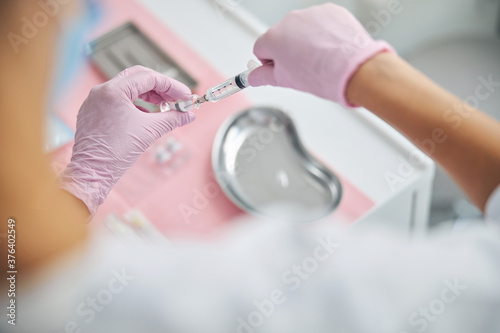 Beautician in latex gloves preparing for an injection