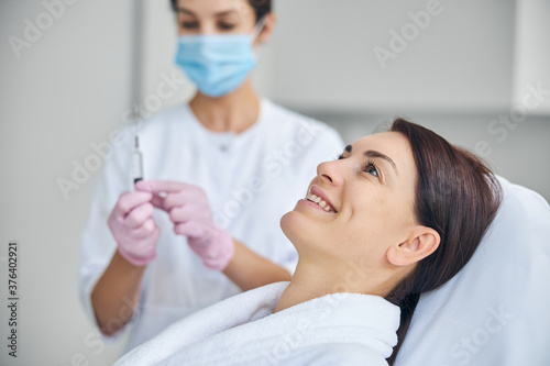 Cosmetician getting ready for injecting a cheerful client