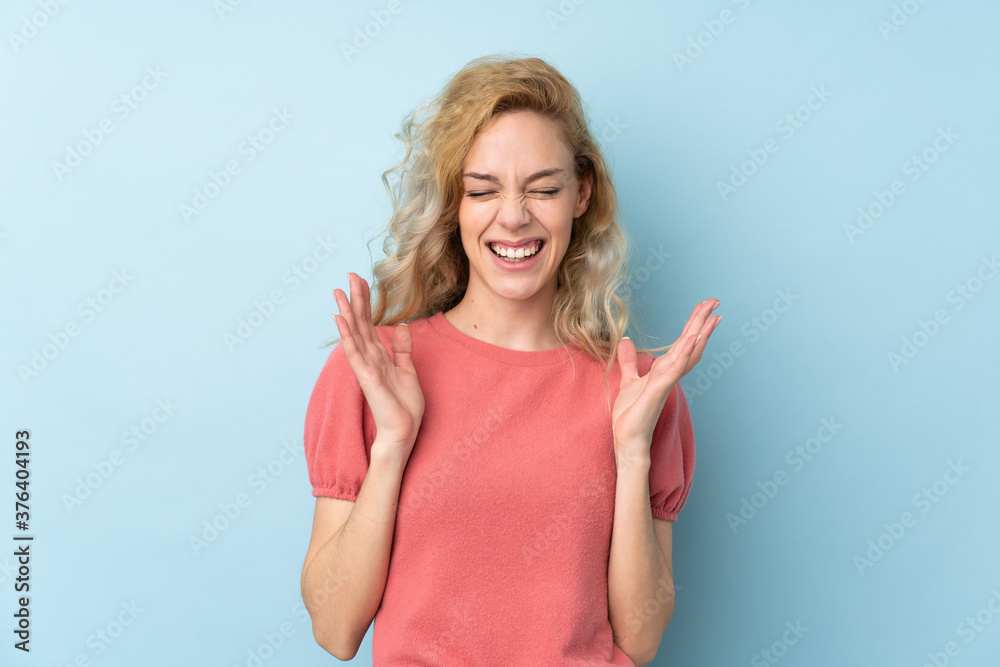 Young blonde woman isolated on blue background laughing