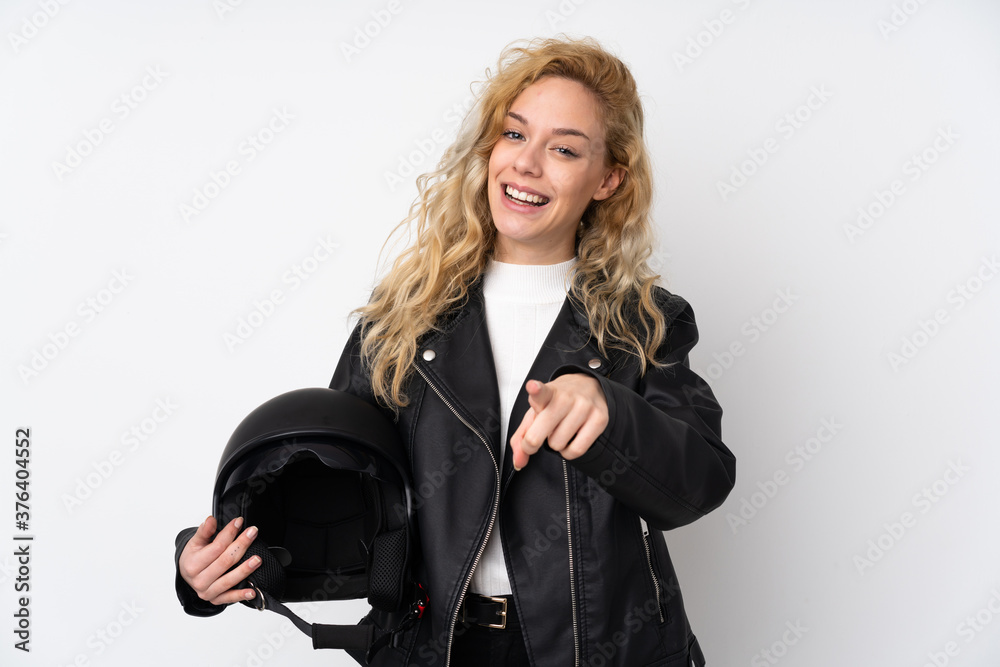 Young blonde woman with a motorcycle helmet isolated on white background points finger at you with a confident expression Young blonde woman with a motorcycle helmet isolated on white background points finger at you with a confident expression