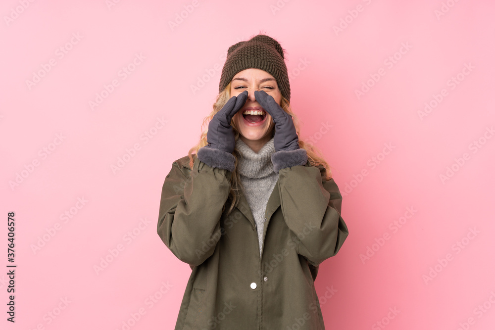 Young girl with winter hat isolated on pink background shouting with mouth wide open Young girl with winter hat isolated on pink background shouting with mouth wide open