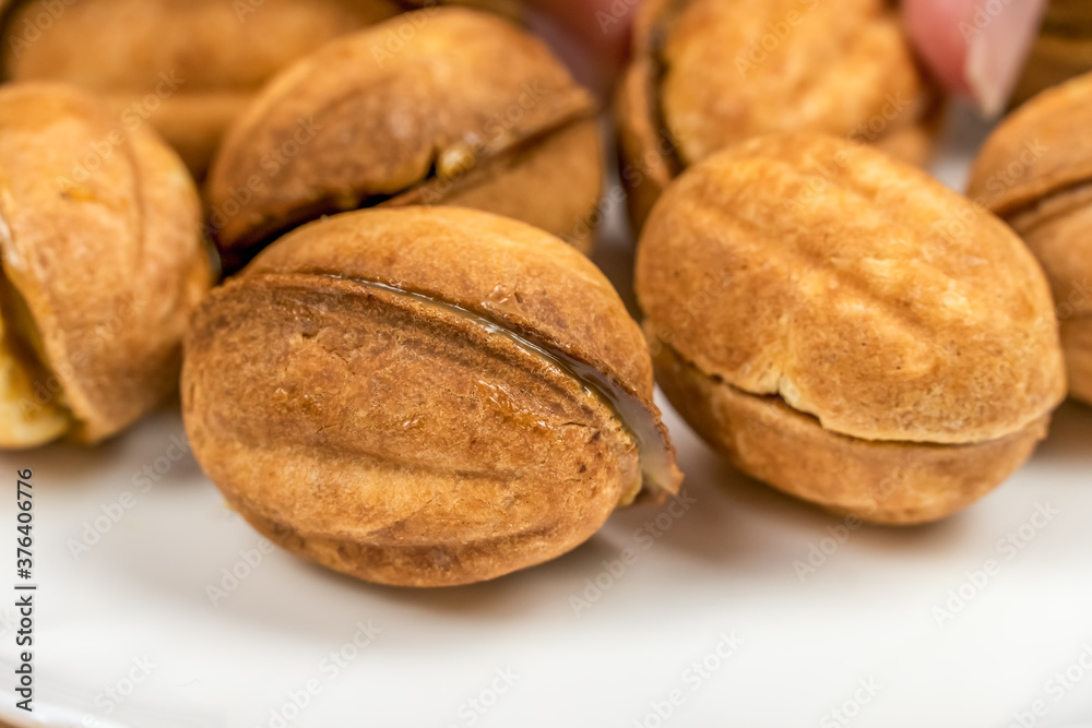 Lots of cookies Nuts with boiled condensed milk on a white plate close up, macro Lots of cookies Nuts with boiled condensed milk on a white plate close up, macro