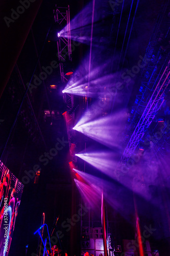 Stage lights. Several projectors in dark. A bright colored spotlight permeates the darkness. Light from the stage, rock concert. Lighting equipment. Several projectors on theatrical lighting system © Elena