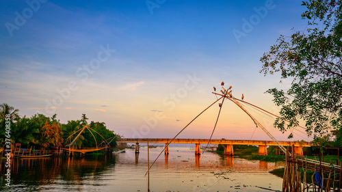 Birds perched on square dip net with bridge at Pakpra canal, Phatthalung, Thailand