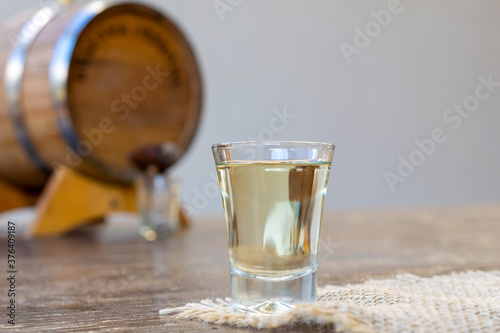 detail of glass of white cachaça and vat on blurred background. space for text. photo