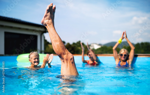 Fototapeta Naklejka Na Ścianę i Meble -  Group of seniors in swimming pool outdoors in backyard, having fun.