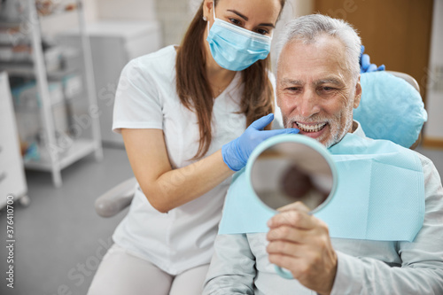 Aging gentleman being happy with his new dental implant photo
