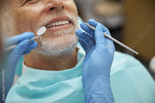 Calm elderly man smiling during dental examination photo