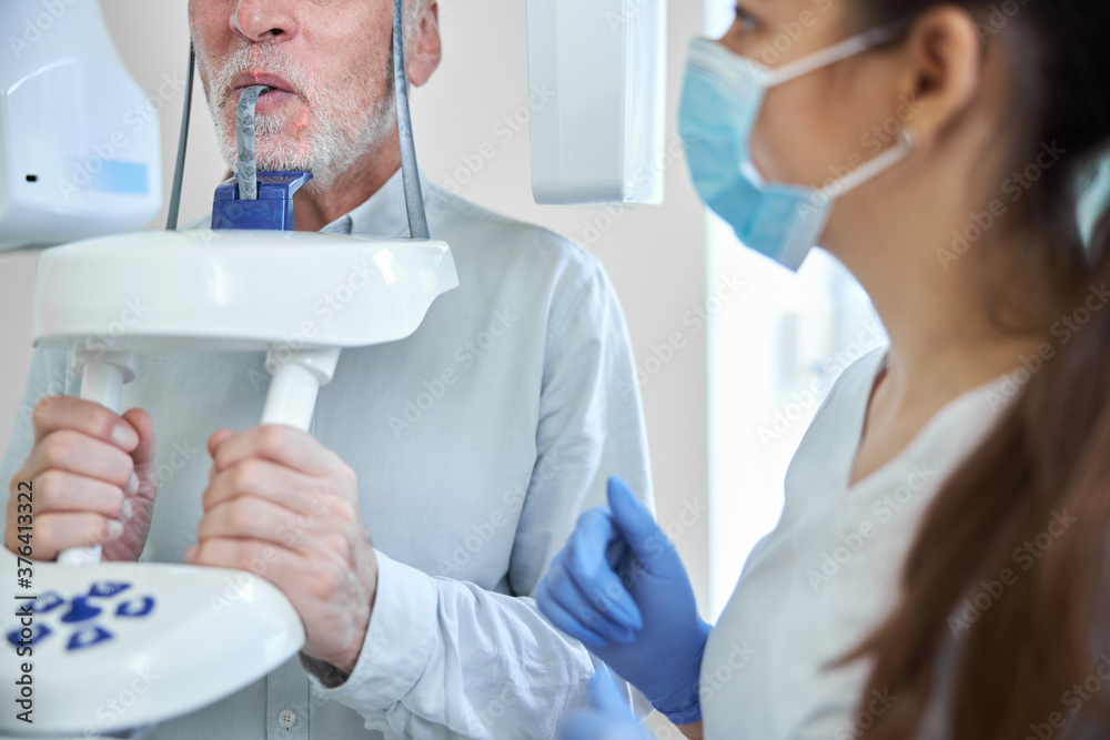 Obraz premium Female dental expert preparing an elderly man for dental x-ray