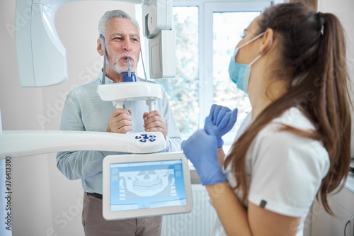 Professional dentist looking at her patient getting x-ray