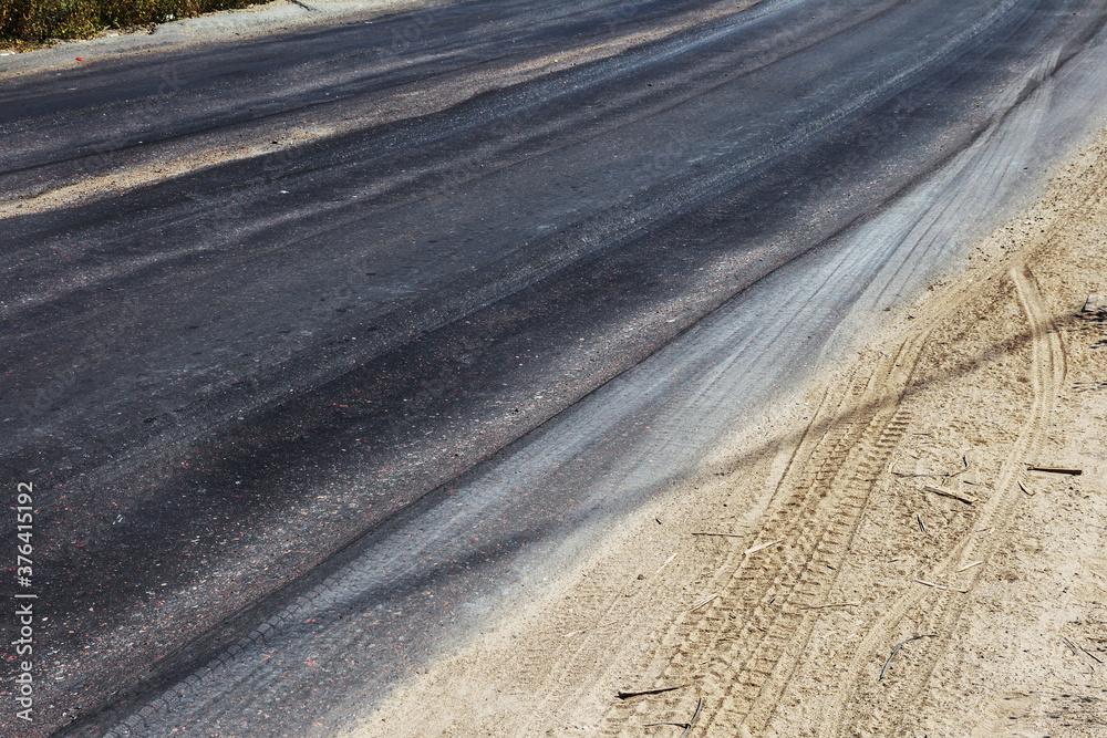 Damaged road, damaged chopped asphalt with potholes and spot. Very bad asphalt road with large trenche. Terrible technology of asphalt production in construction of road. Soft Asphalt melts from heat Damaged road, damaged chopped asphalt with potholes and spot. Very bad asphalt road with large trenche. Terrible technology of asphalt production in construction of road. Soft Asphalt melts from heat