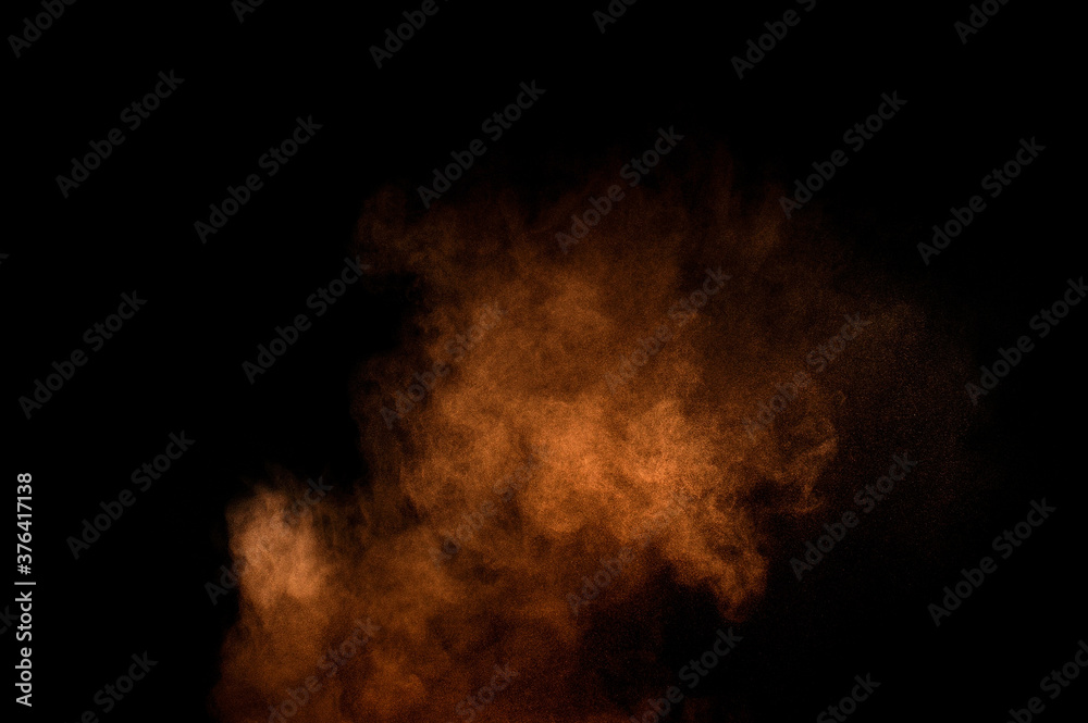 Orange powder explosion on black background. Colored powder cloud. Colorful dust explode. Paint Holi.