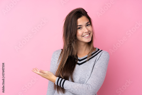 Teenager girl over isolated pink background extending hands to the side for inviting to come © luismolinero