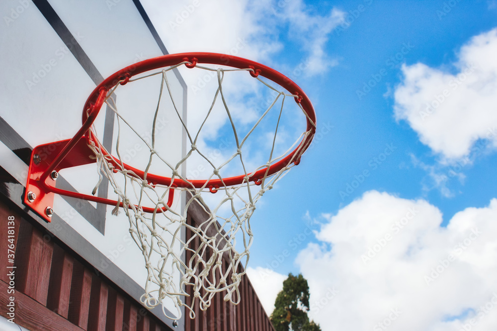 Basketball hoop with netting from underneath with a blue sky background