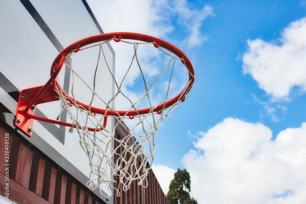 Basketball hoop with netting from underneath with a blue sky background Basketball hoop with netting from underneath with a blue sky background