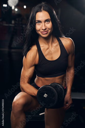Smiley sportswoman holding a dumbbell while working out
