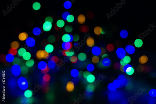  Сохранить Скачать изображение для предпросмотра Abstract Colorful Bokeh Background. Blurred garland on a black background. New Year or Christmas card with colorful lights.